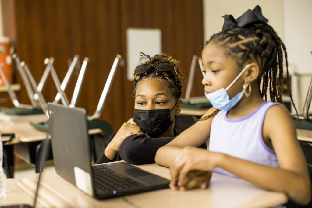 A teacher and student looking at a laptop together