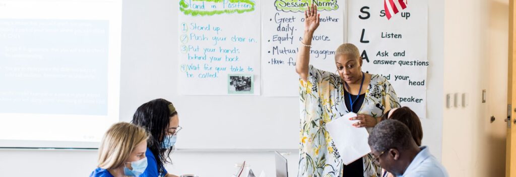 A teacher standing at the front of a classroom with colleagues